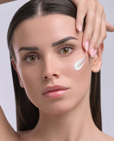 Model applying Lucis Nurturing Day Cream on the cheek — The Nine Aurora day cream texture.